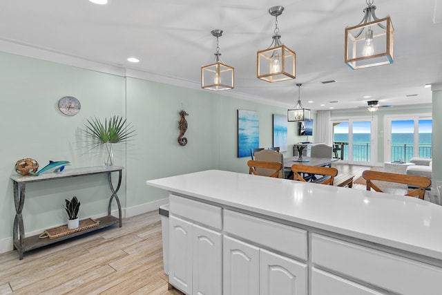 kitchen with white cabinets, light wood finished floors, baseboards, light countertops, and decorative light fixtures
