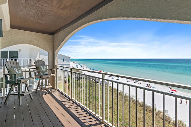 balcony featuring a view of the beach and a water view