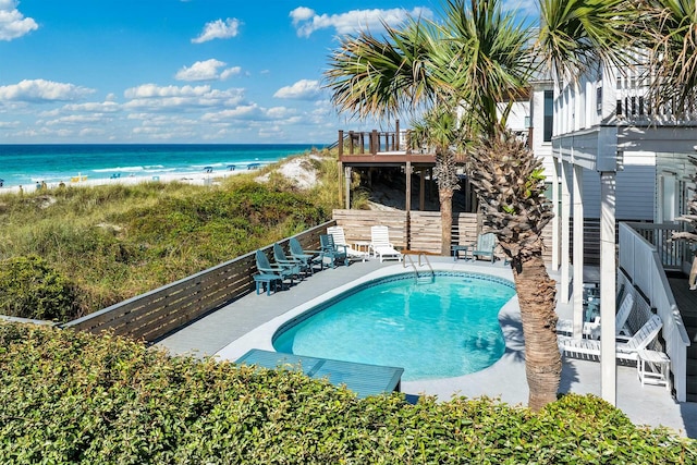 pool with a view of the beach, a patio, a water view, and stairway