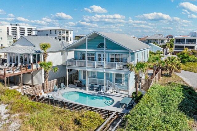 rear view of house featuring a balcony, fence, a patio, a fenced in pool, and stairs