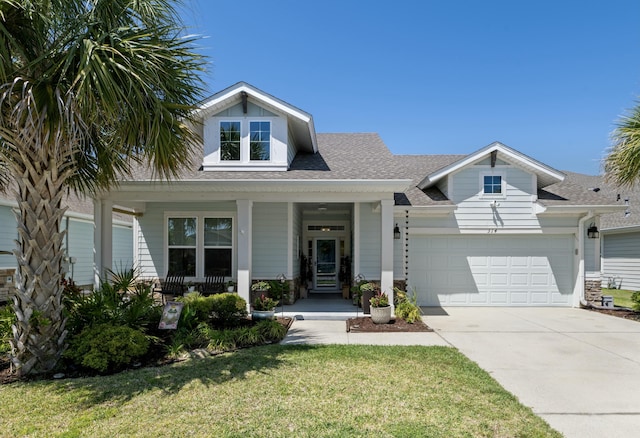 view of front facade featuring roof with shingles, a porch, concrete driveway, an attached garage, and a front yard