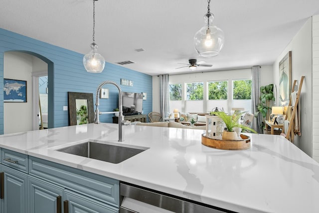 kitchen featuring a sink, hanging light fixtures, open floor plan, ceiling fan, and arched walkways