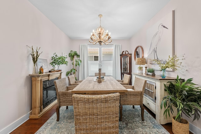dining space with baseboards, a chandelier, dark wood-type flooring, and a premium fireplace