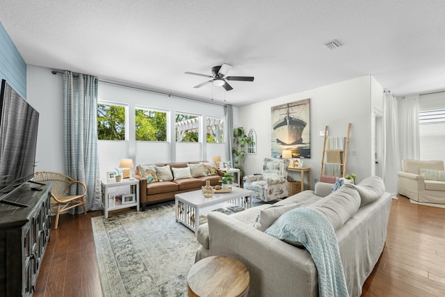 living area with visible vents, dark wood-type flooring, and ceiling fan