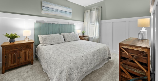 bedroom with wainscoting, a decorative wall, and carpet