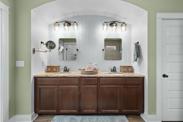 bathroom with baseboards, wood finished floors, a sink, and double vanity