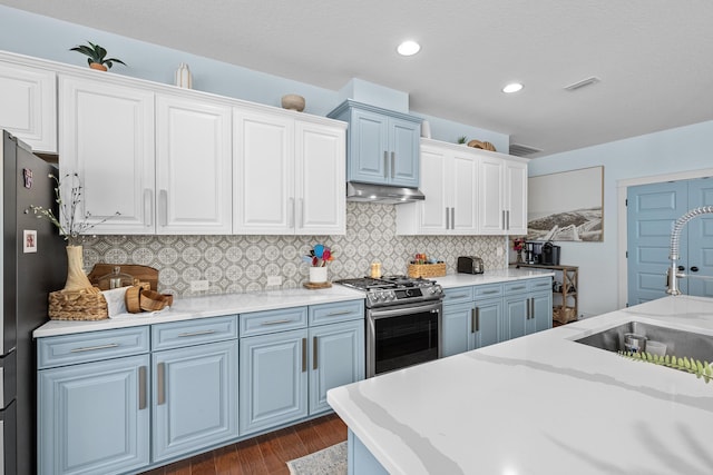 kitchen with under cabinet range hood, backsplash, a sink, appliances with stainless steel finishes, and dark wood-style flooring