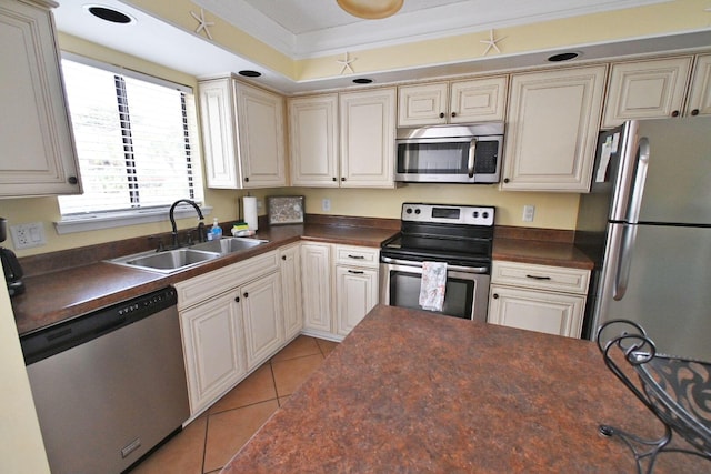 kitchen featuring light tile patterned floors, dark countertops, appliances with stainless steel finishes, and a sink