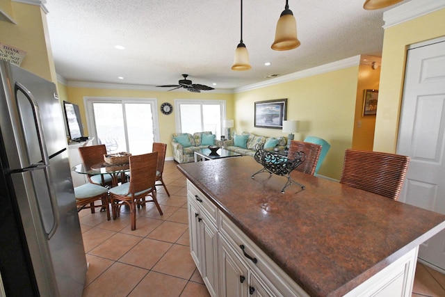 kitchen with light tile patterned floors, dark countertops, ceiling fan, and freestanding refrigerator