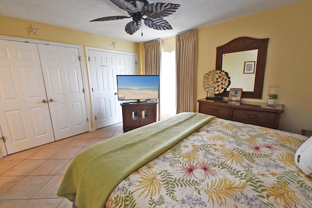 tiled bedroom with a ceiling fan and multiple closets