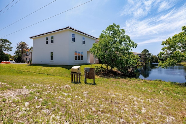 view of property exterior with a yard, a water view, and stucco siding