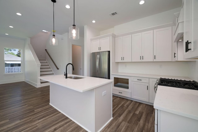 kitchen featuring white cabinets, an island with sink, dark wood-style floors, a sink, and freestanding refrigerator