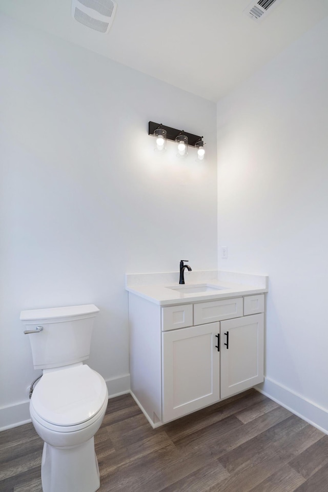 bathroom with wood finished floors, visible vents, toilet, and baseboards