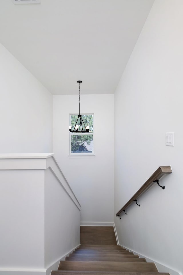 stairs featuring an inviting chandelier, wood finished floors, visible vents, and baseboards