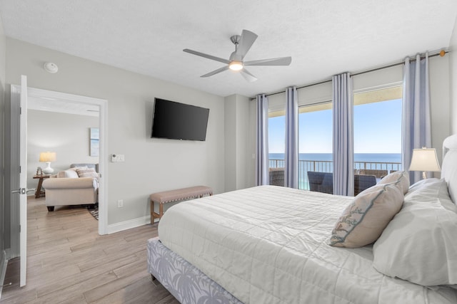 bedroom with multiple windows, a textured ceiling, light wood-style floors, and access to exterior