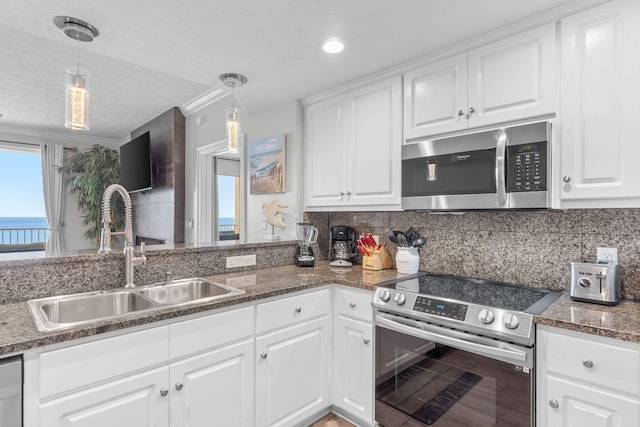 kitchen with white cabinets, hanging light fixtures, appliances with stainless steel finishes, and a sink