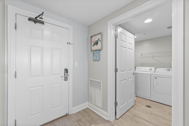 foyer featuring independent washer and dryer, light wood-type flooring, visible vents, and baseboards