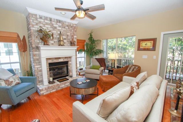 living area featuring a brick fireplace, ceiling fan, and wood finished floors