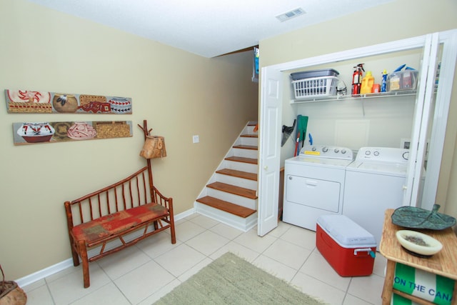 laundry room with laundry area, visible vents, washing machine and dryer, light tile patterned floors, and baseboards