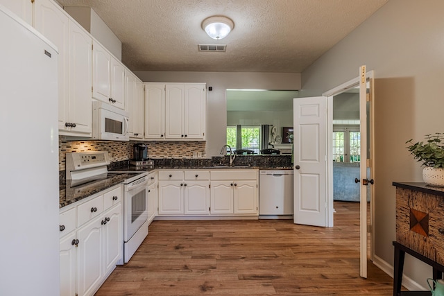 kitchen with wood finished floors, a textured ceiling, white appliances, white cabinetry, and visible vents