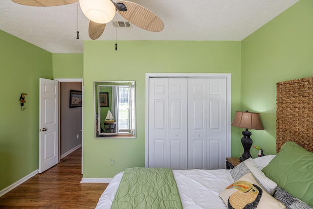 bedroom featuring baseboards, visible vents, a ceiling fan, wood finished floors, and a closet