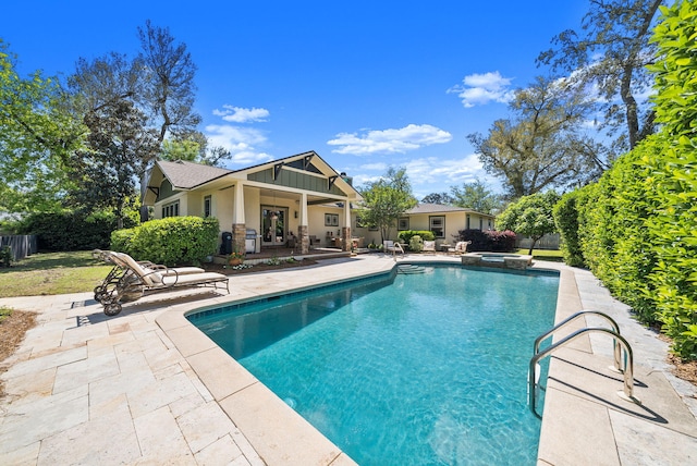 view of pool with fence, a patio, and a pool with connected hot tub