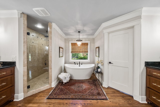 bathroom featuring a freestanding tub, wood finished floors, vanity, and a stall shower