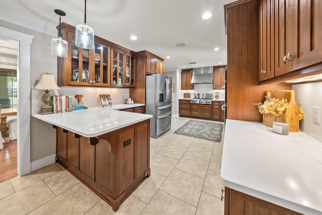 kitchen with stainless steel fridge with ice dispenser, light countertops, wall chimney range hood, a peninsula, and glass insert cabinets