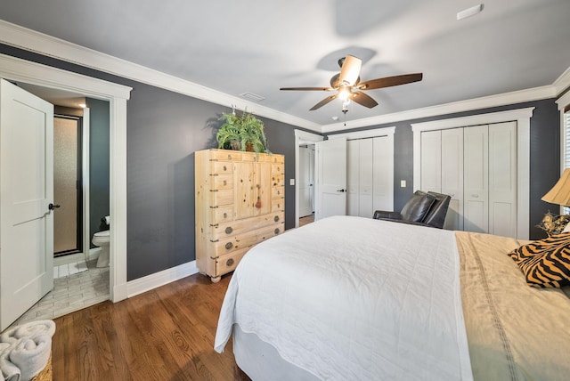 bedroom with dark wood finished floors, visible vents, baseboards, crown molding, and multiple closets