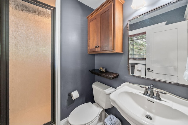 bathroom with baseboards, toilet, a stall shower, and a sink