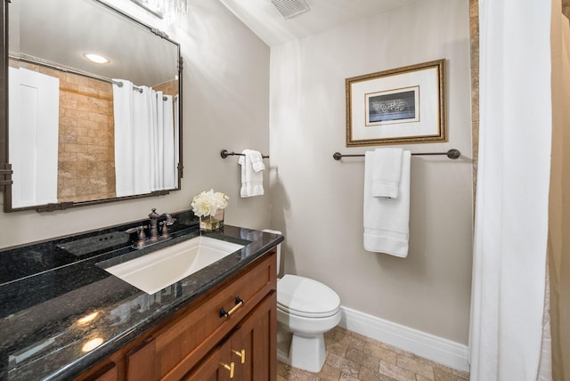 bathroom featuring stone tile flooring, toilet, baseboards, visible vents, and vanity