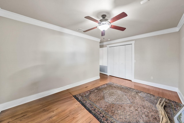 unfurnished bedroom with visible vents, wood finished floors, baseboards, and ornamental molding