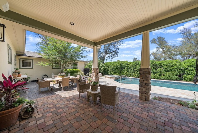 view of patio / terrace featuring outdoor dining area and a pool with connected hot tub