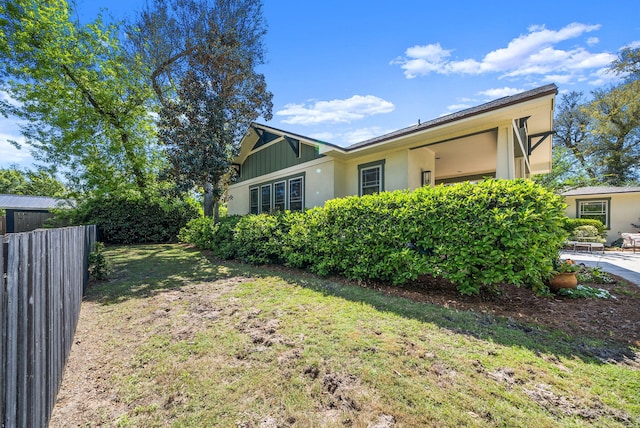 view of property exterior with stucco siding, fence, and a yard