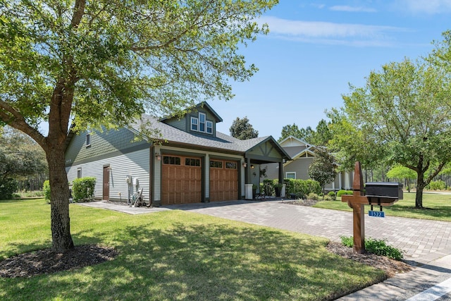 view of front of house with an attached garage, driveway, a shingled roof, and a front yard