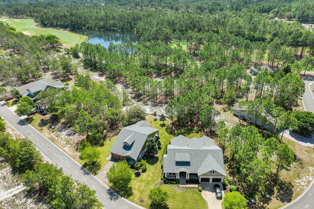 drone / aerial view with view of golf course, a water view, and a wooded view