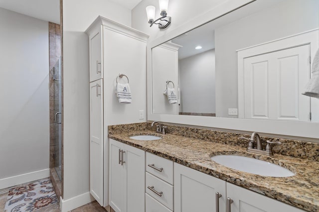 full bathroom featuring baseboards, a sink, double vanity, and a stall shower
