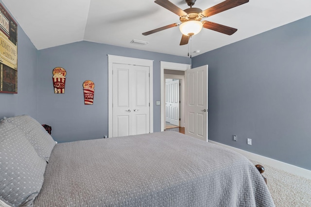 carpeted bedroom featuring lofted ceiling, visible vents, a ceiling fan, a closet, and baseboards