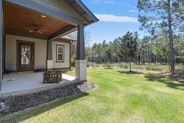 view of yard featuring a ceiling fan, a patio, and an outdoor fire pit