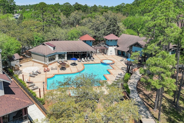 pool with a patio area, an in ground hot tub, fence, and a view of trees