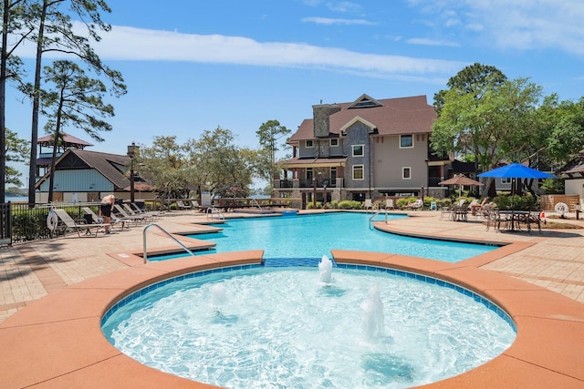 community pool with fence, a community hot tub, and a patio