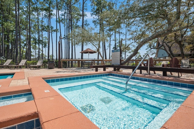 view of swimming pool featuring playground community, a hot tub, and a patio