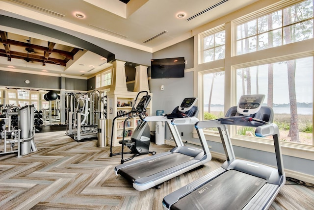 exercise room featuring decorative columns, a towering ceiling, and a wealth of natural light
