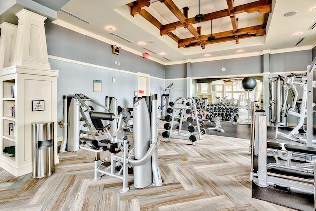 gym with a towering ceiling, coffered ceiling, visible vents, decorative columns, and light colored carpet