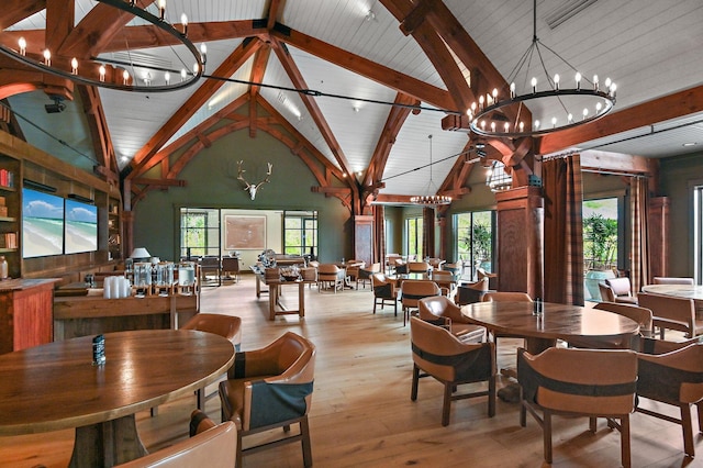 dining space with hardwood / wood-style flooring, a chandelier, and high vaulted ceiling