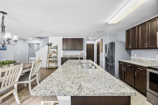 3129 Partridge Dr, Crestview, FL 32539 - kitchen featuring a sink, appliances with stainless steel finishes, dark brown cabinets, an island with sink, and a textured ceiling
