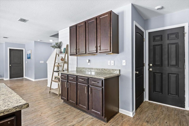 3129 Partridge Dr, Crestview, FL 32539 - kitchen featuring baseboards, light wood-style floors, a textured ceiling, dark brown cabinetry, and light stone counters