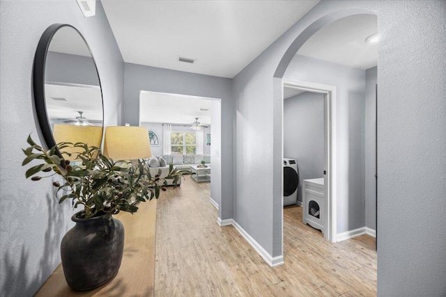 3129 Partridge Dr, Crestview, FL 32539 - hall featuring washer / clothes dryer, arched walkways, wood finished floors, and baseboards