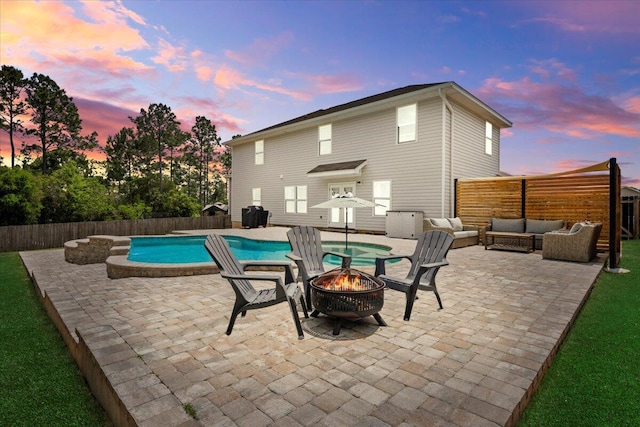 3129 Partridge Dr, Crestview, FL 32539 - pool at dusk featuring an outdoor living space with a fire pit, a patio area, and a fenced backyard