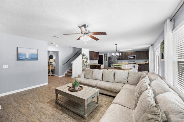 3129 Partridge Dr, Crestview, FL 32539 - living area featuring ceiling fan, a chandelier, stairs, light wood-type flooring, and baseboards